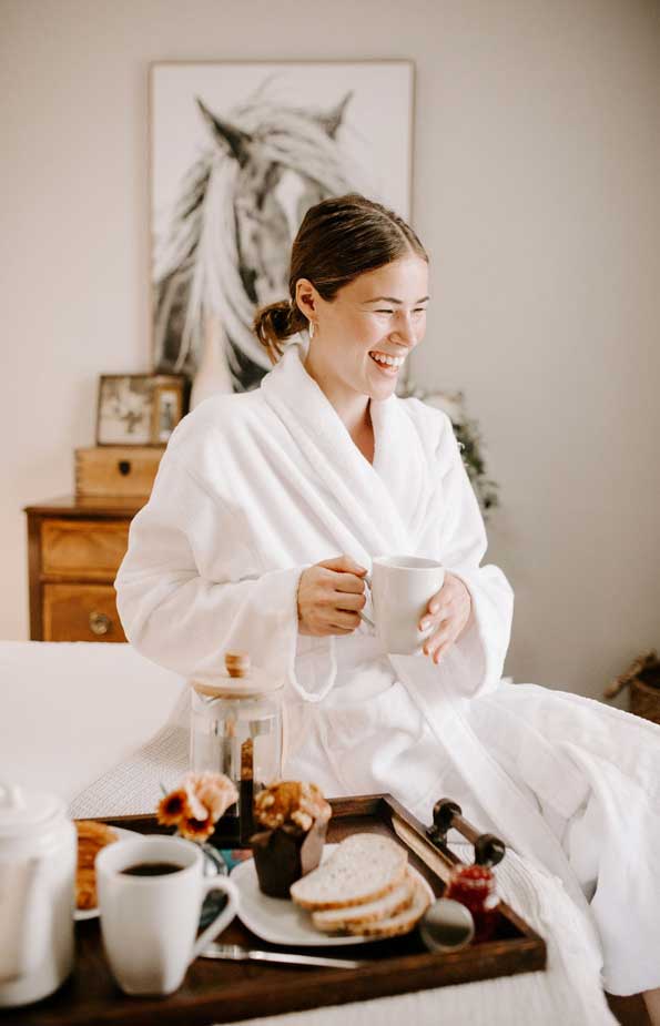 woman laughing on bed with coffee